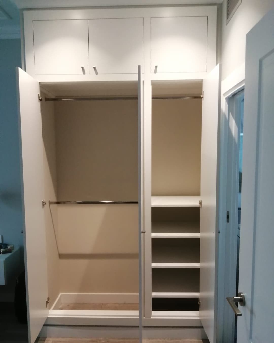 Armario empotrado blanco de dos cuerpos, uno con barras para colgar la ropa y otro con baldas.