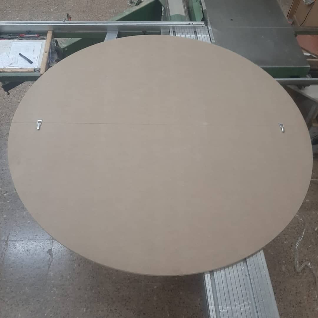 Tablero grande, circular, de madera de color tostado, con dos ganchos 