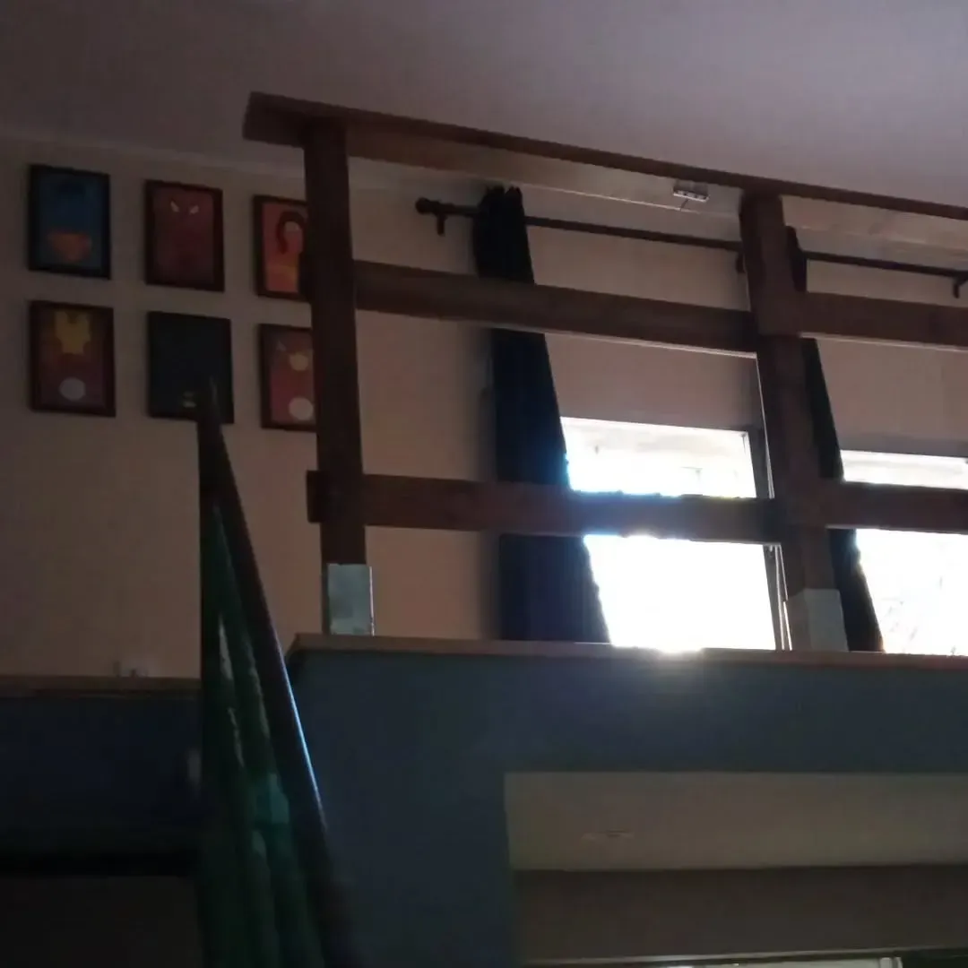 Barandilla de madera sobre una plataforma elevada, con obra de arte enmarcada en la pared de arriba.