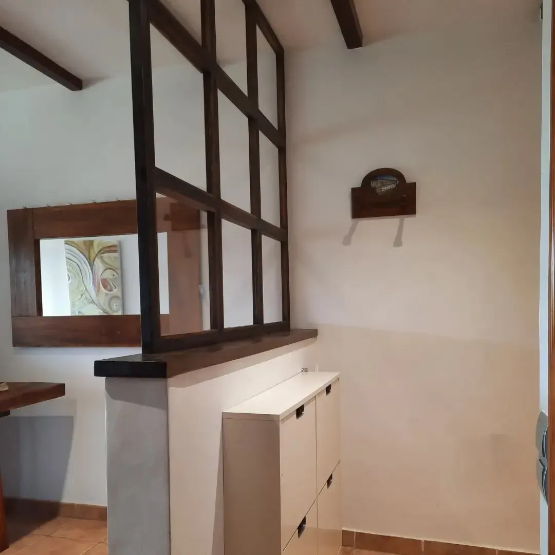 Entrada con vigas de madera, rejilla decorativa, espejo y zapatero.