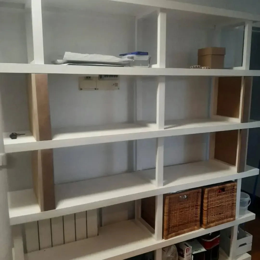 Estantería empotrada blanca con múltiples compartimentos. 