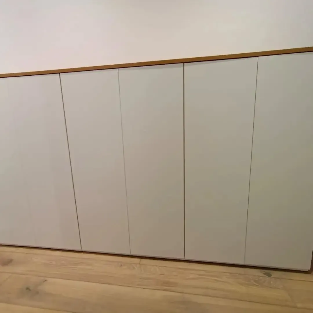 Puertas de gabinete grises instaladas a lo largo de un piso de madera clara.