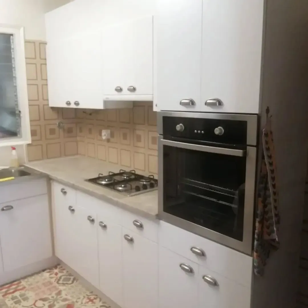 Gabinetes de cocina blancos con horno, estufa y encimera neutra.