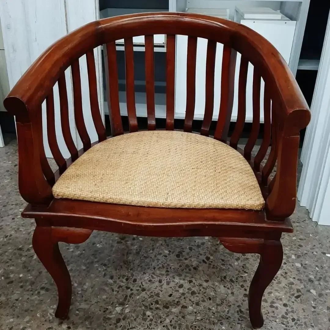 Sillón de madera con respaldo arqueado y asiento tejido.