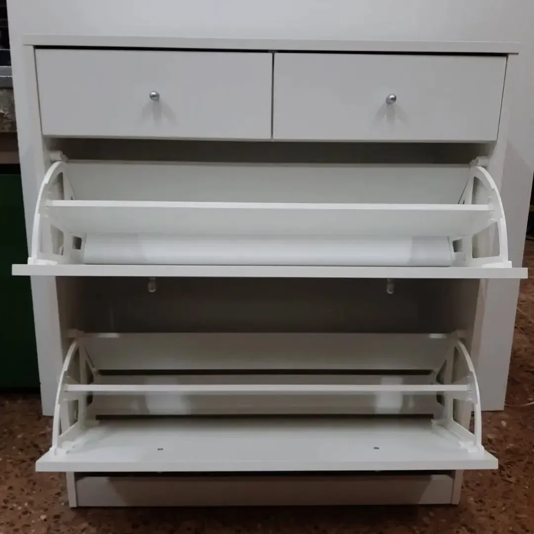 Zapatero blanco con dos cajones en la parte superior y dos estantes zapateros inclinables en la parte inferior.