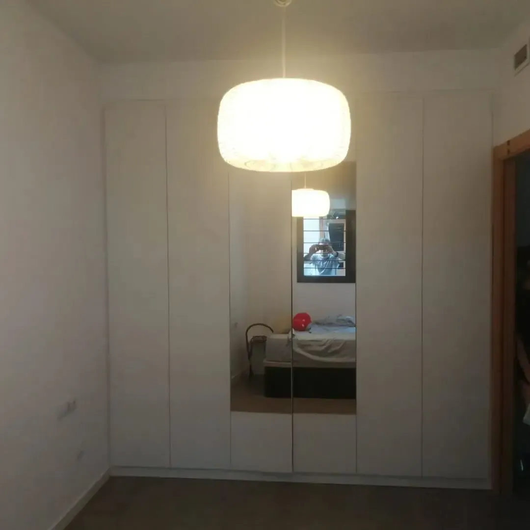 Armario blanco con espejo y lámpara colgante en una habitación.