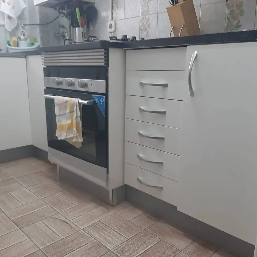 Rincón de cocina con gabinetes blancos, horno y piso de baldosas.