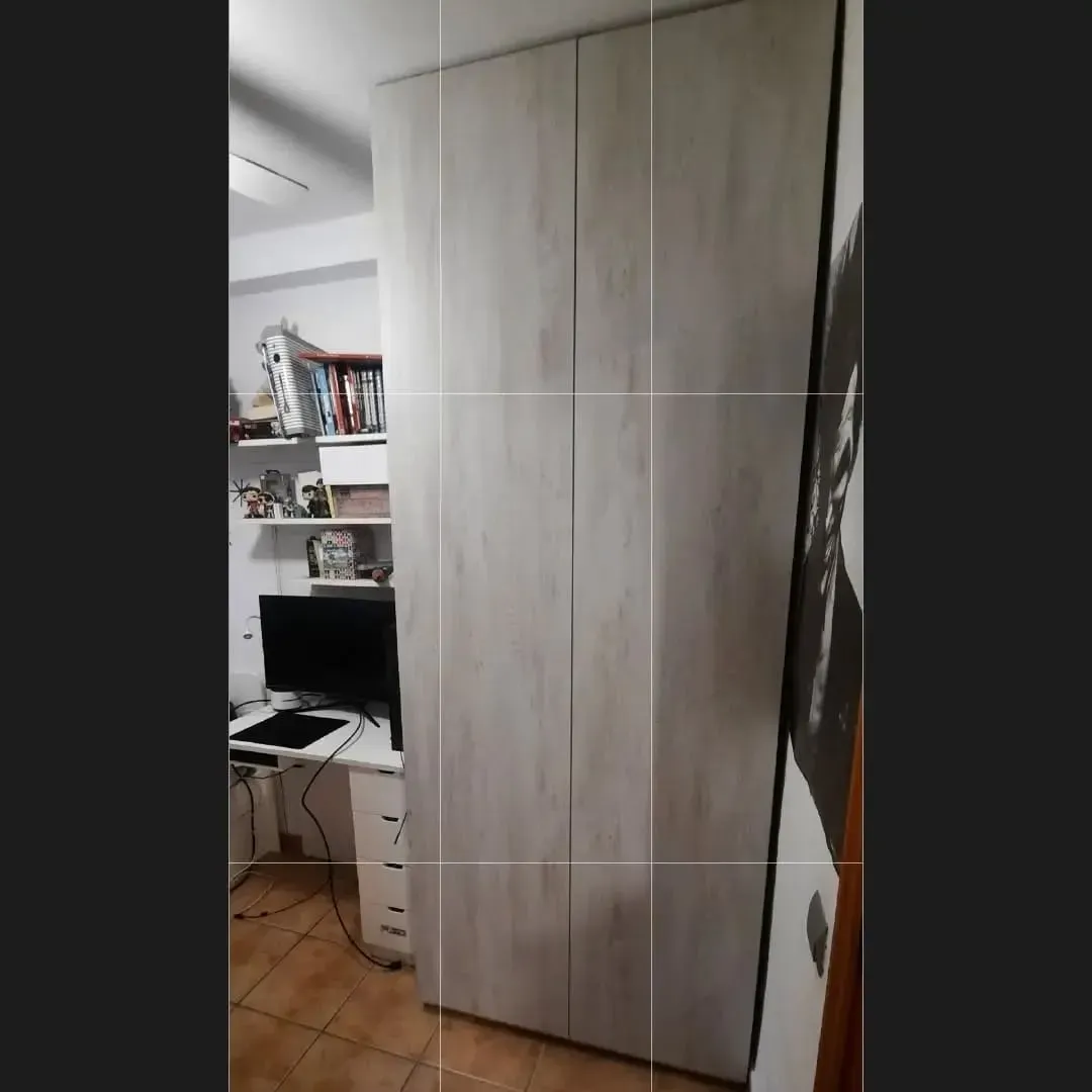 Armario alto de madera clara con cuatro puertas en una habitación. 