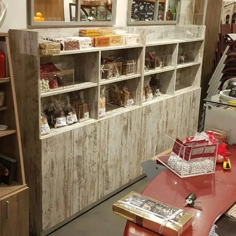 Estantes de golosinas empaquetadas en una tienda, con una mesa roja y una caja de regalo en primer plano.