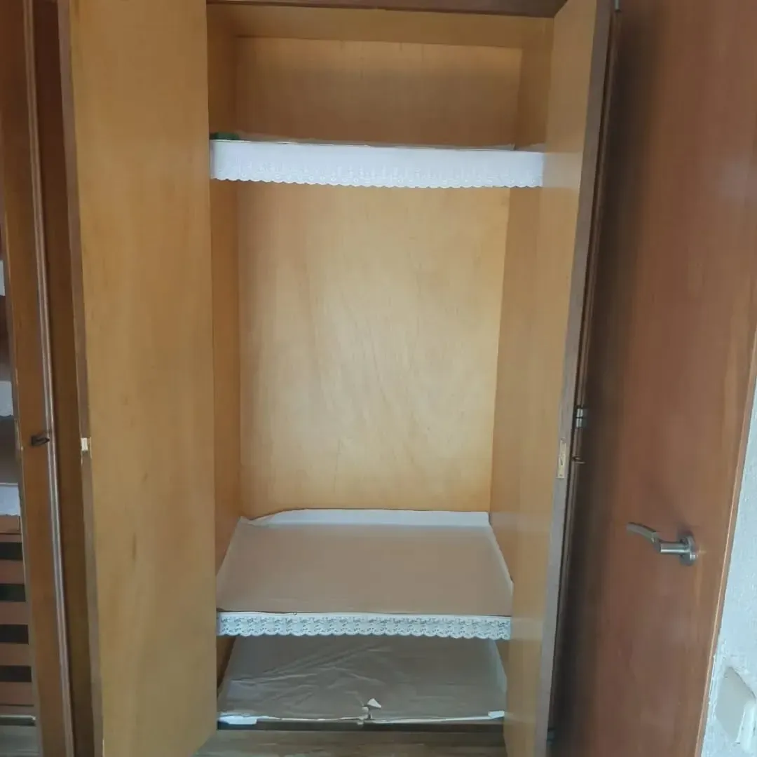 Armario de madera vacío con dos estantes, puertas abiertas.