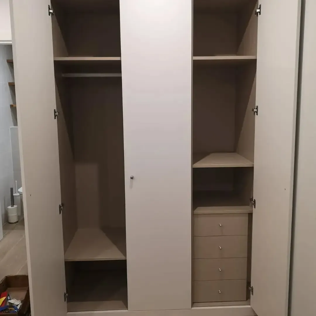 Armario abierto en color claro con barra para colgar ropa, estantes y cajones.