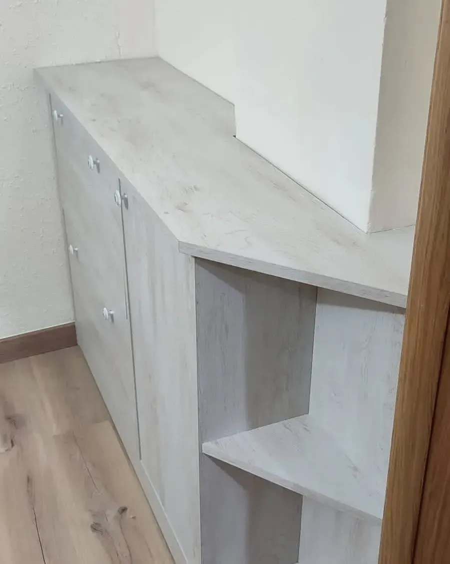 Mueble de madera clara con puertas y estantes abiertos adosado a la pared.