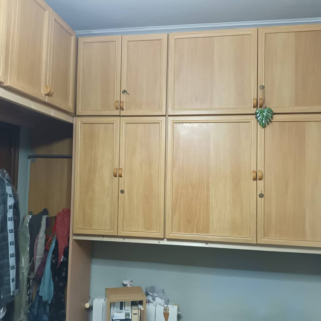 Armarios de madera con puertas cerradas, algunos con pequeños tiradores, encima de una pared con un armario a la izquierda.