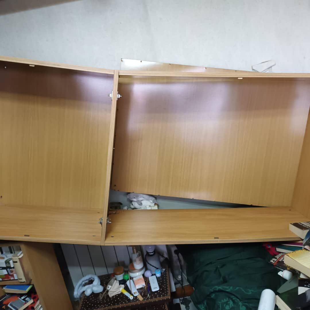 Dos estantes de madera fijados a una pared, uno de ellos inclinado hacia abajo.