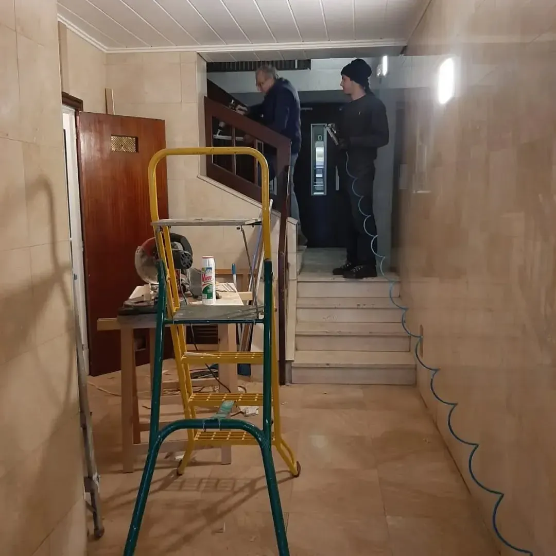 Dos personas renovando un pasillo: una cerca de las escaleras