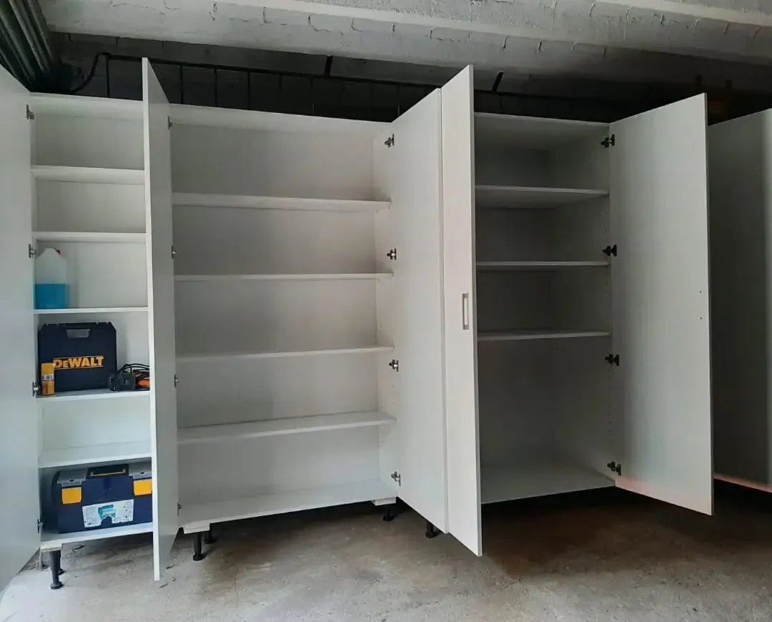 Armarios de almacenamiento blancos con puertas abiertas, llenos de estantes y herramientas.