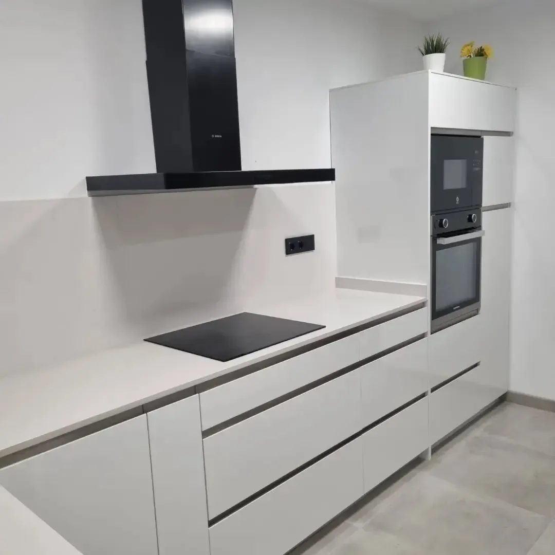 Cocina blanca moderna con electrodomésticos negros.