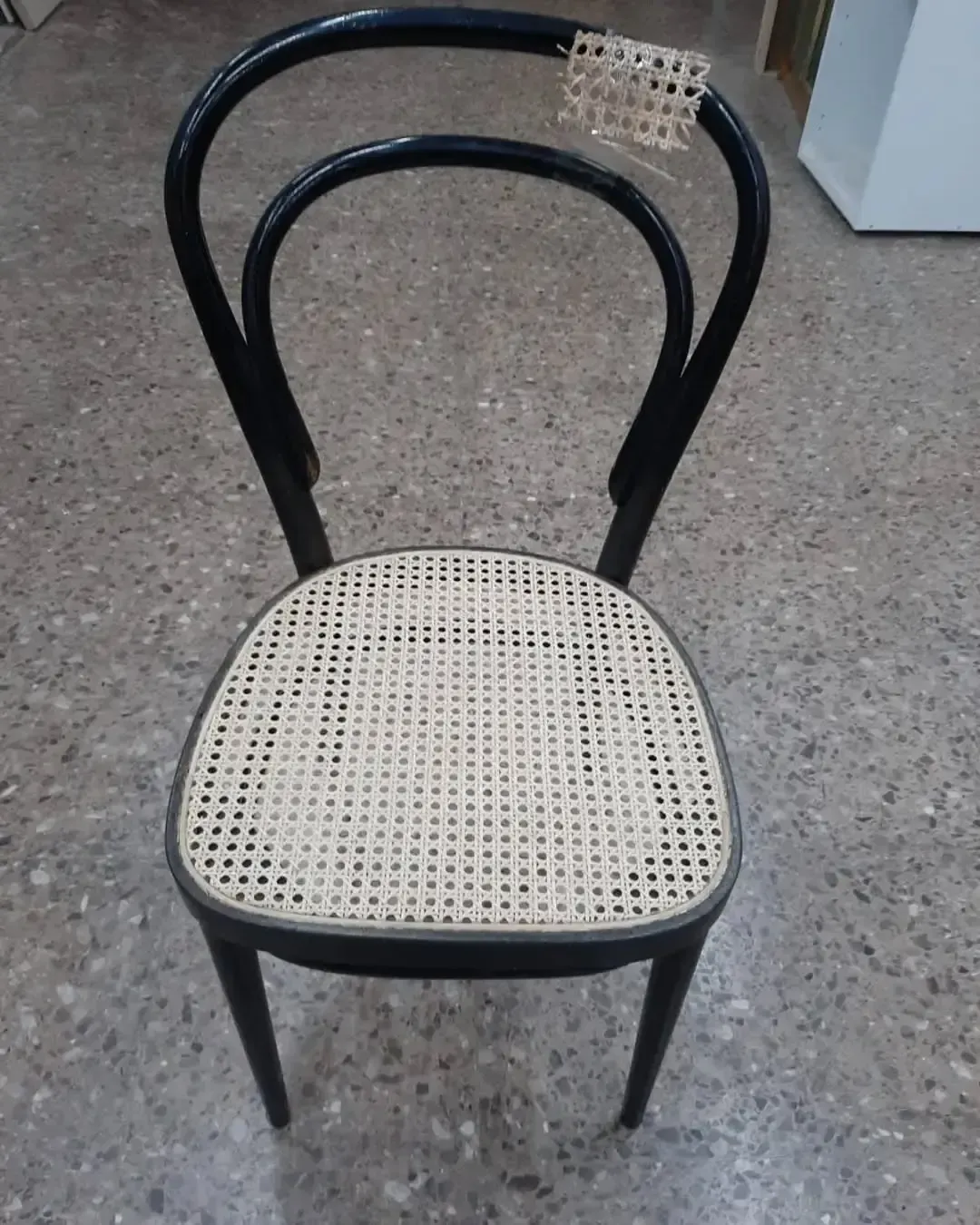 Silla de madera negra con asiento y respaldo de caña tejida.