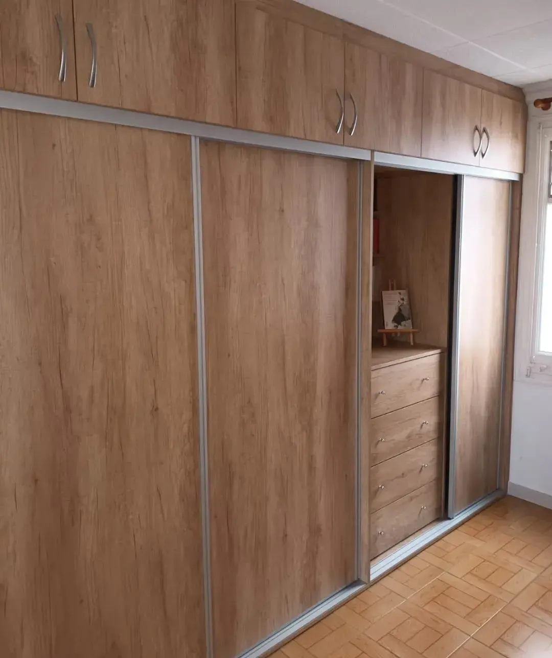 Armario de madera clara con puertas corredizas y espacio de almacenamiento