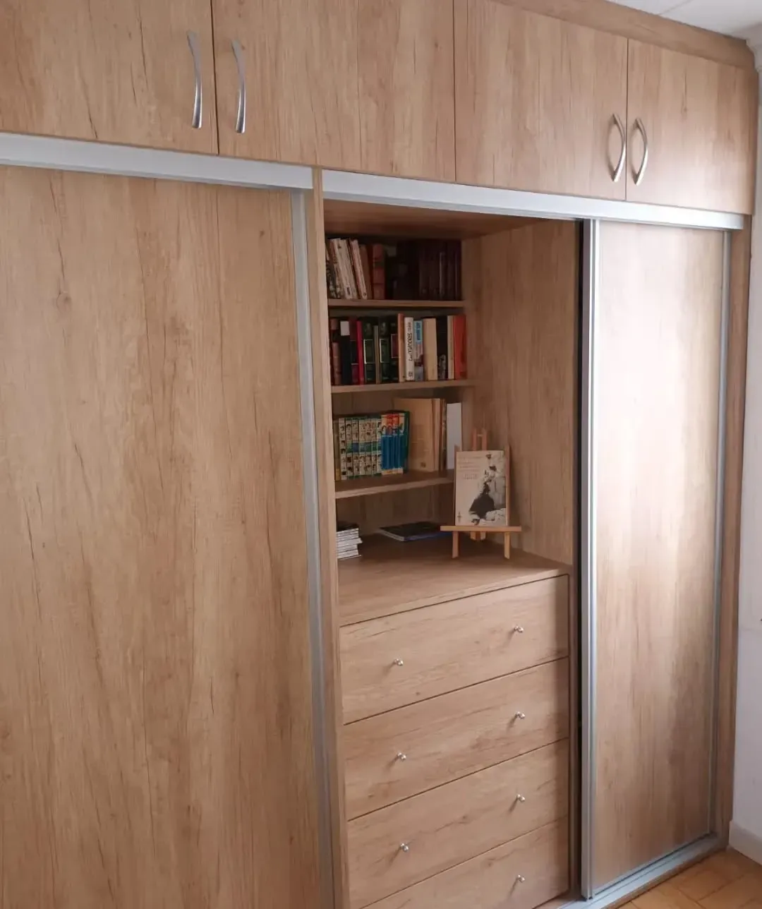 Armario de madera con puertas correderas, que contiene cajones y estantería.