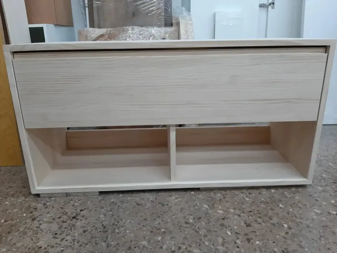 Mueble de madera clara con cajón y dos estantes abiertos.