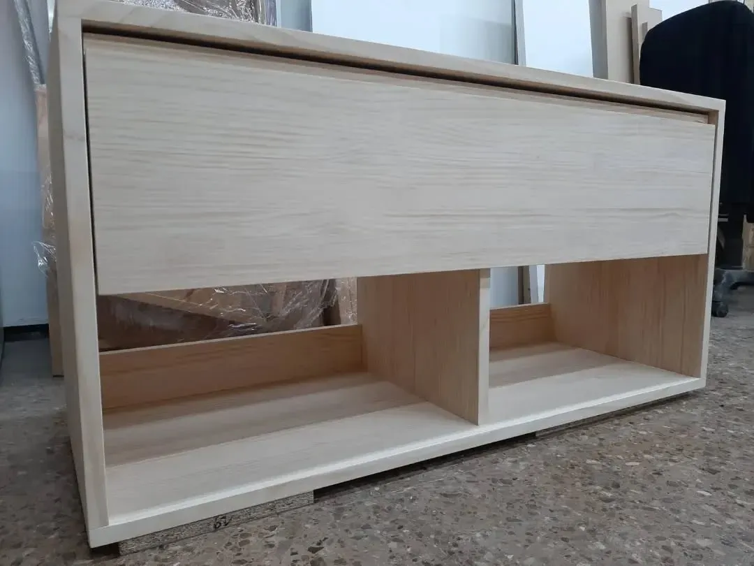 Mueble de madera con cajón y dos estantes abiertos.