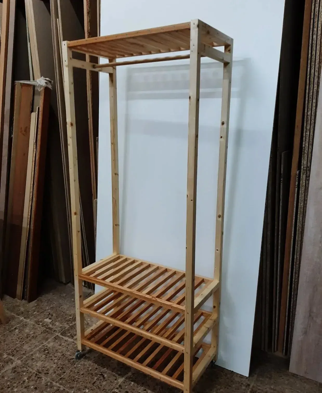 Perchero de madera con estantes y barra para colgar.