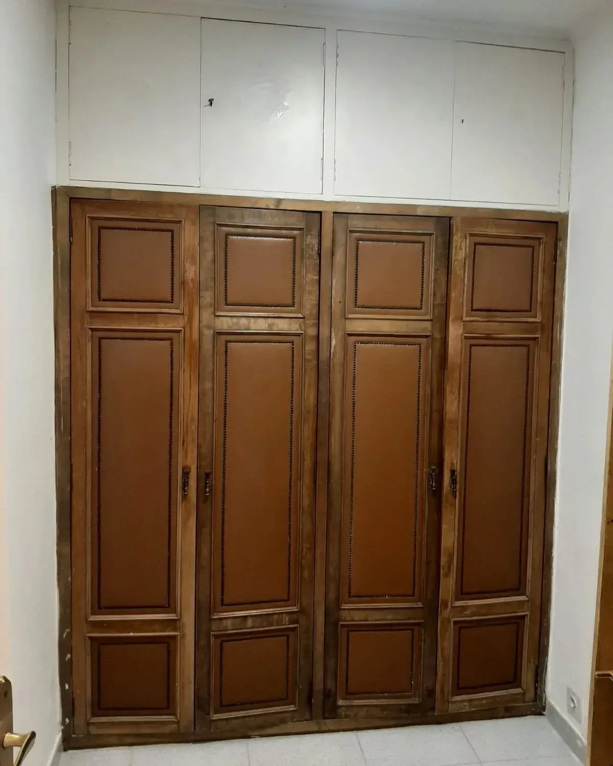 Armario de madera con paneles marrones y muebles superiores de color blanco.