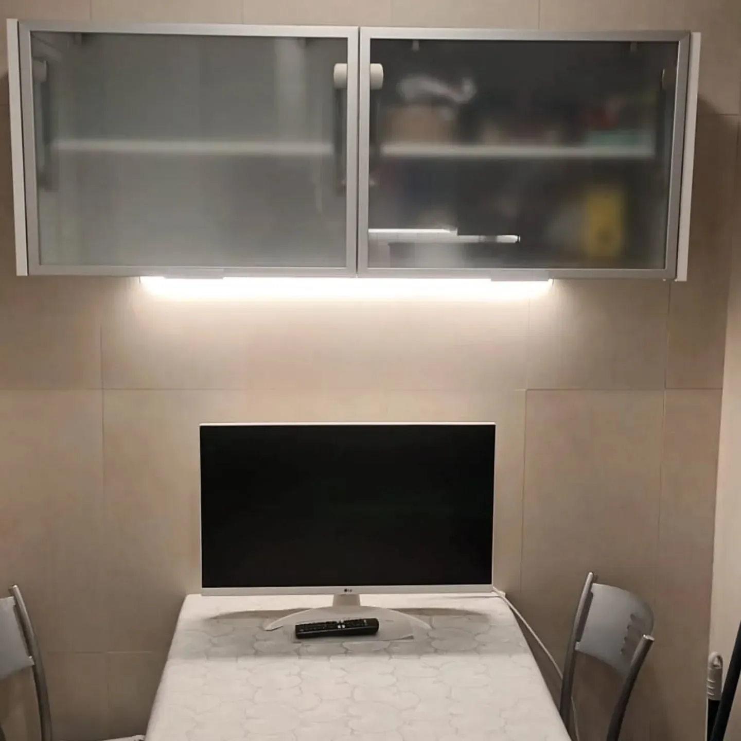 Armarios de cocina sobre una mesa con televisor. Dos sillas a cada lado.