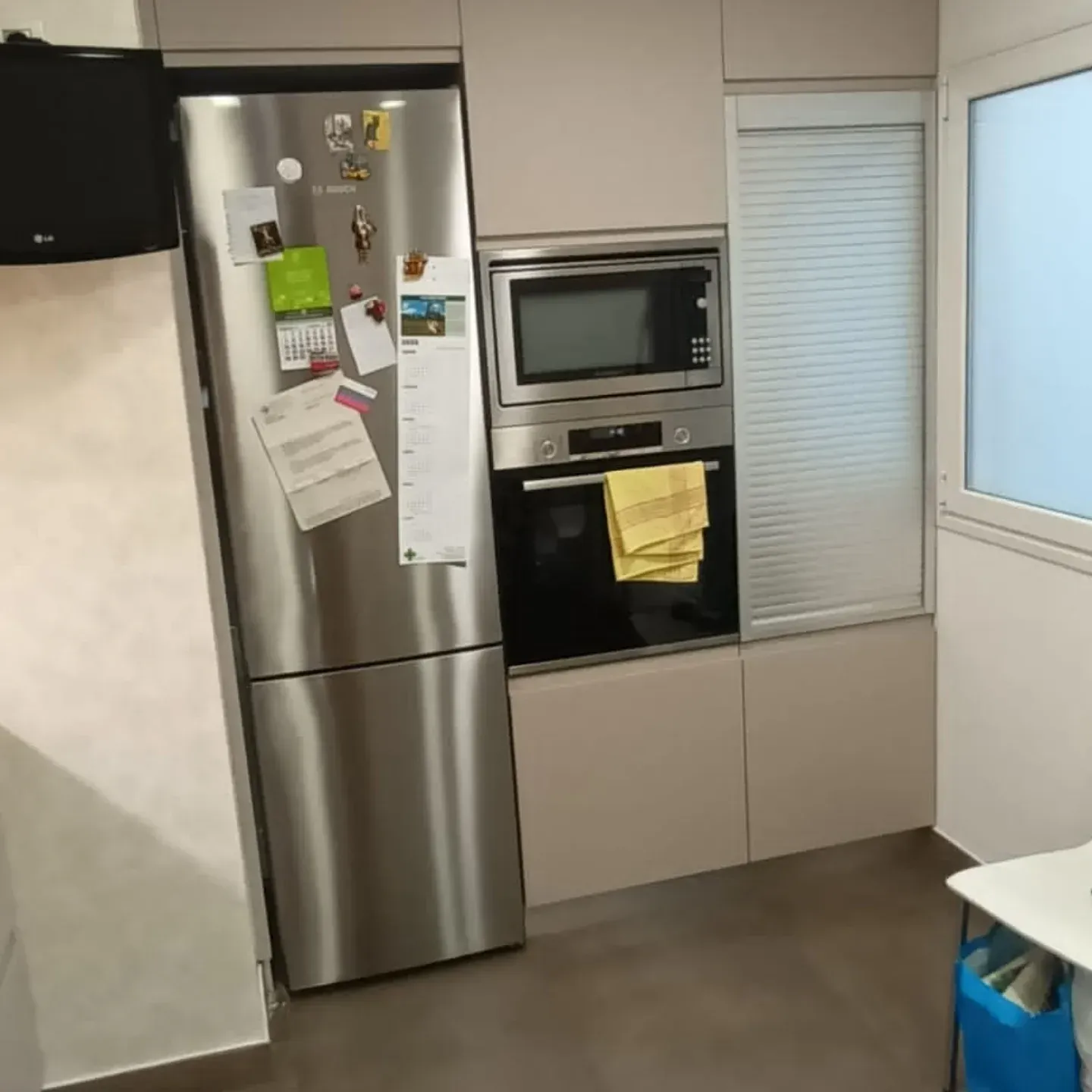 Refrigerador, microondas y horno de acero inoxidable integrados en un moderno mueble de cocina.