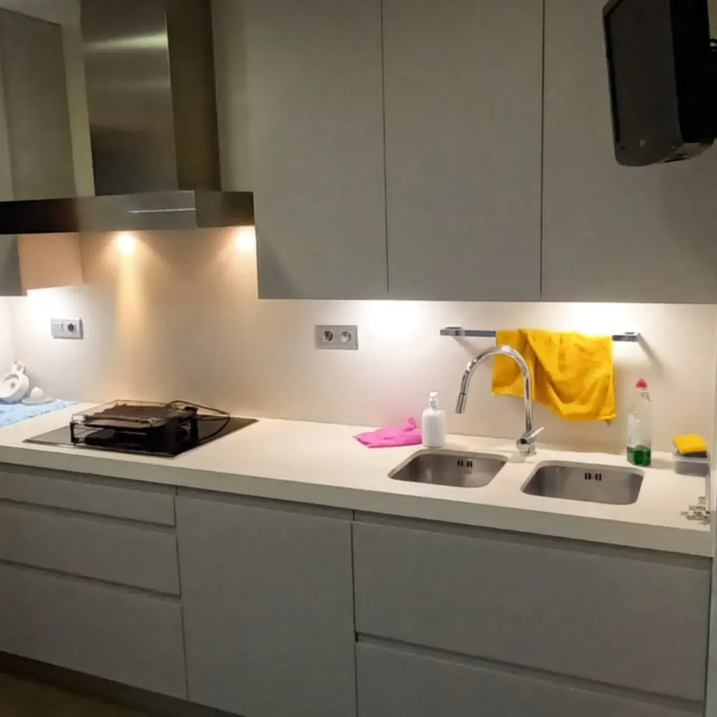 Cocina moderna con gabinetes blancos, campana extractora de acero inoxidable y fregadero doble.