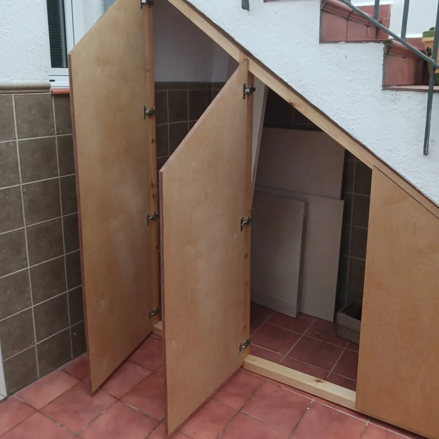 Las puertas de madera se abren bajo la escalera y revelan espacio de almacenamiento.