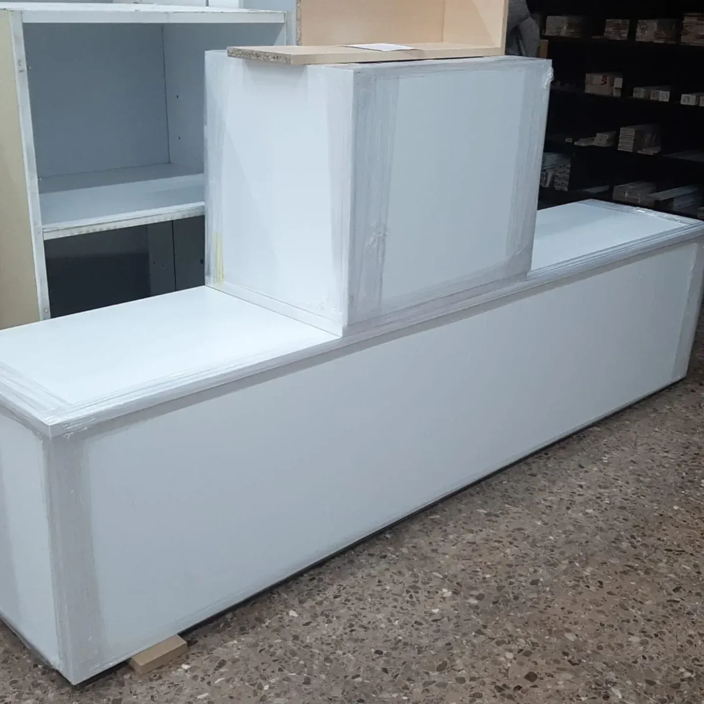 Unidades de almacenamiento rectangulares blancas apiladas sobre un suelo de hormigón. Otra unidad al fondo.