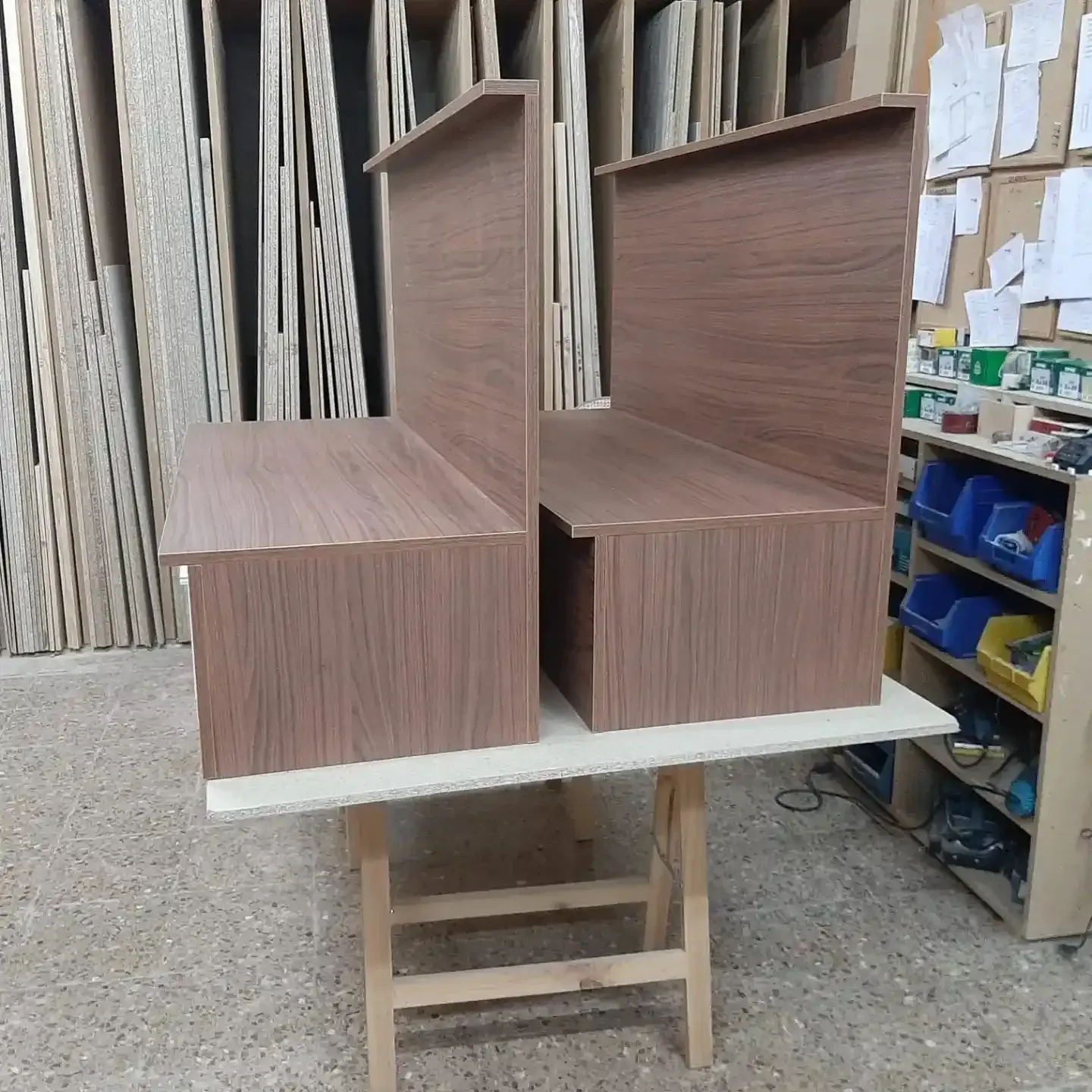 Dos bancos de madera con respaldo vertical sobre una mesa de trabajo, en un taller.