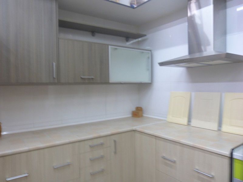 Cocina con gabinetes, encimeras y campana extractora en tonos claros. Se muestran ejemplos de puertas de gabinetes.