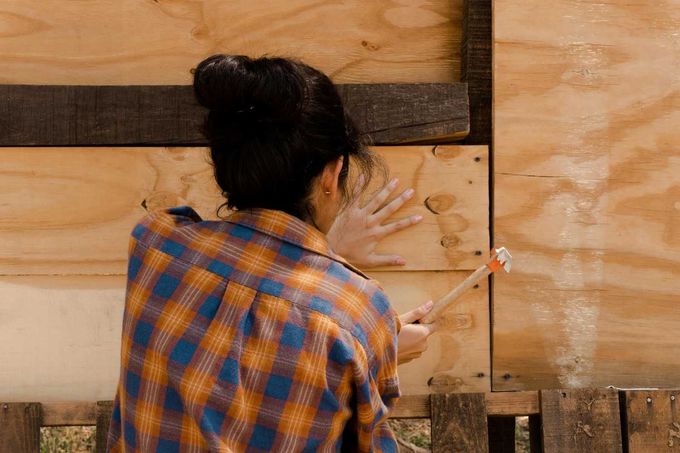 Persona con camisa a cuadros martillando un panel de madera.