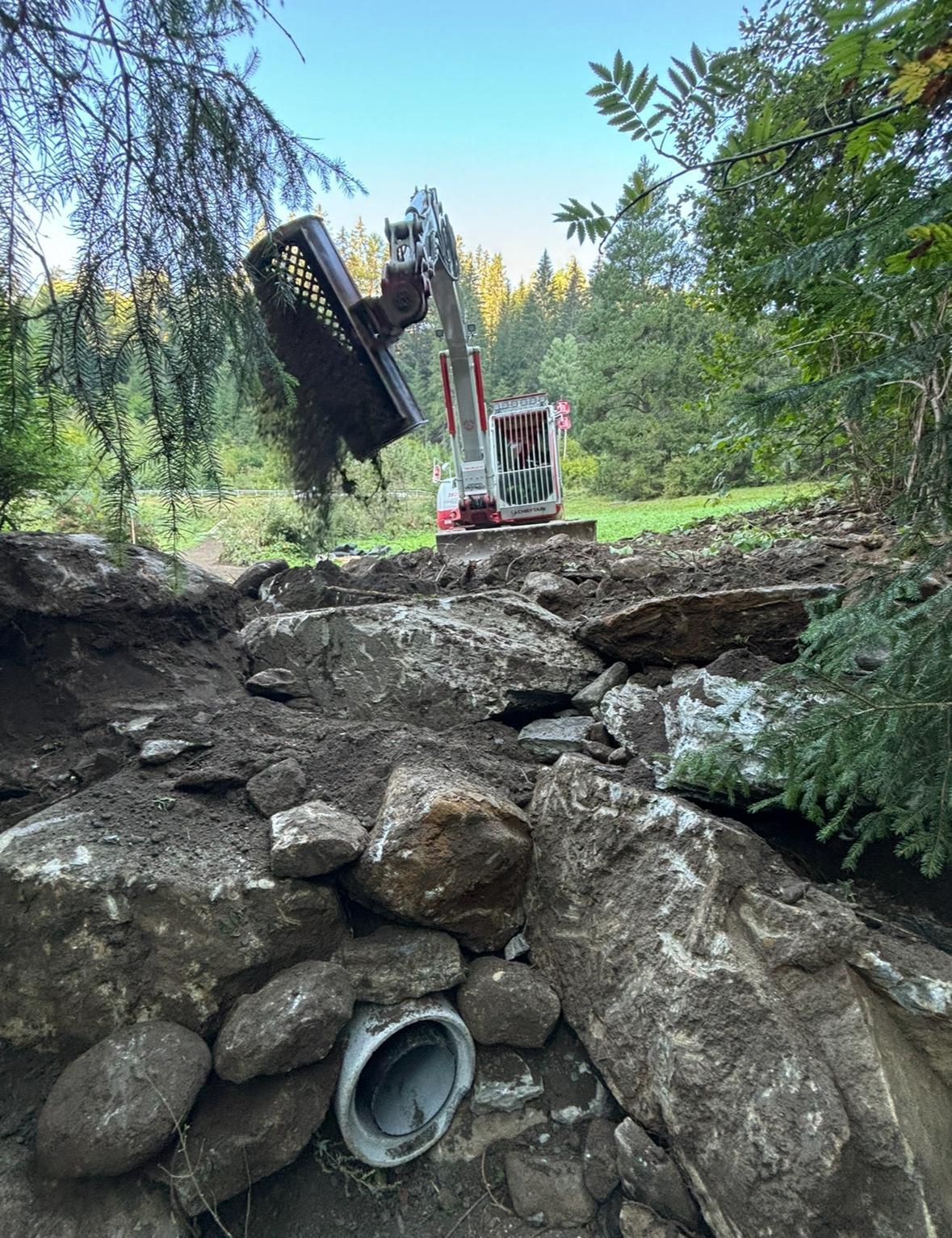 Ein blauer Muldenkipper von der von der Ulrich Koch Transporte GmbH steht am Rand einer unbefestigten Strasse.