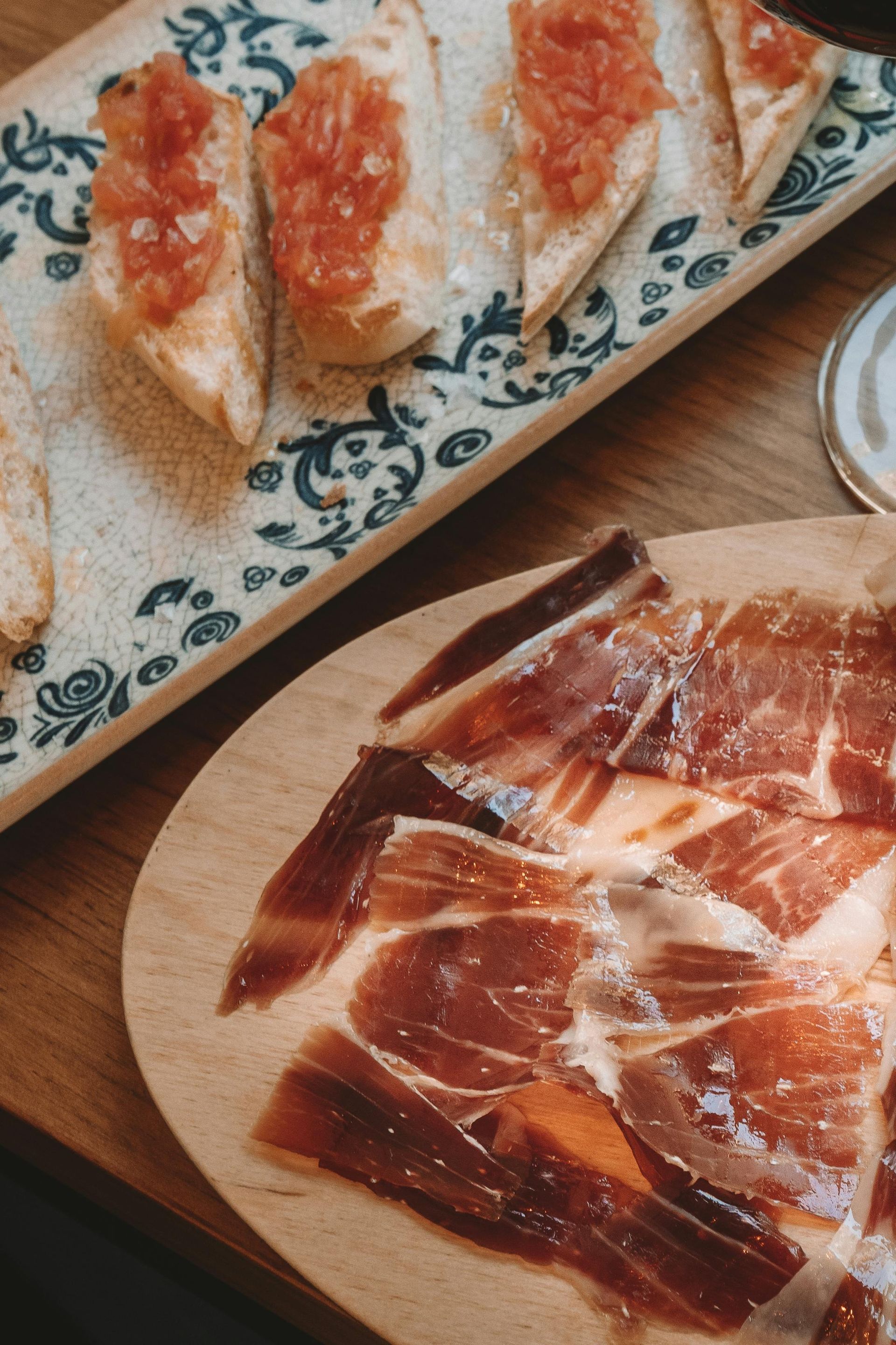 Tapas españolas: pan con tomate y jamón curado en lonchas sobre tablas de madera.
