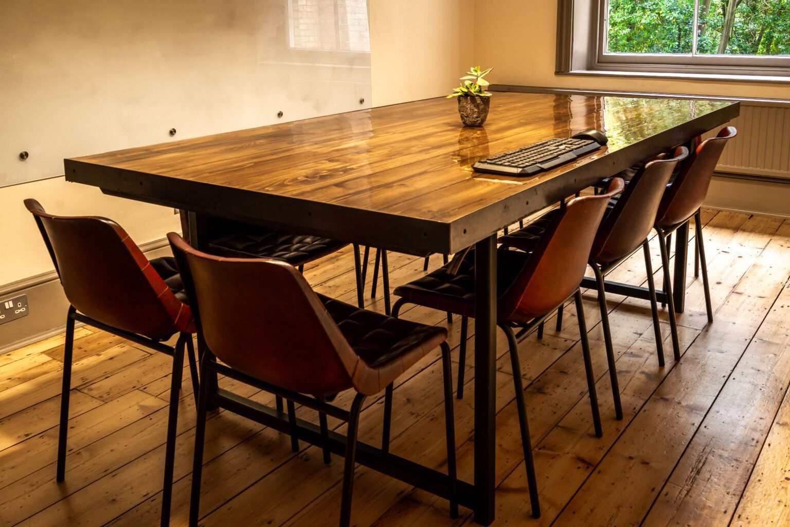 Large wooden table with eight chairs in a room with a window.