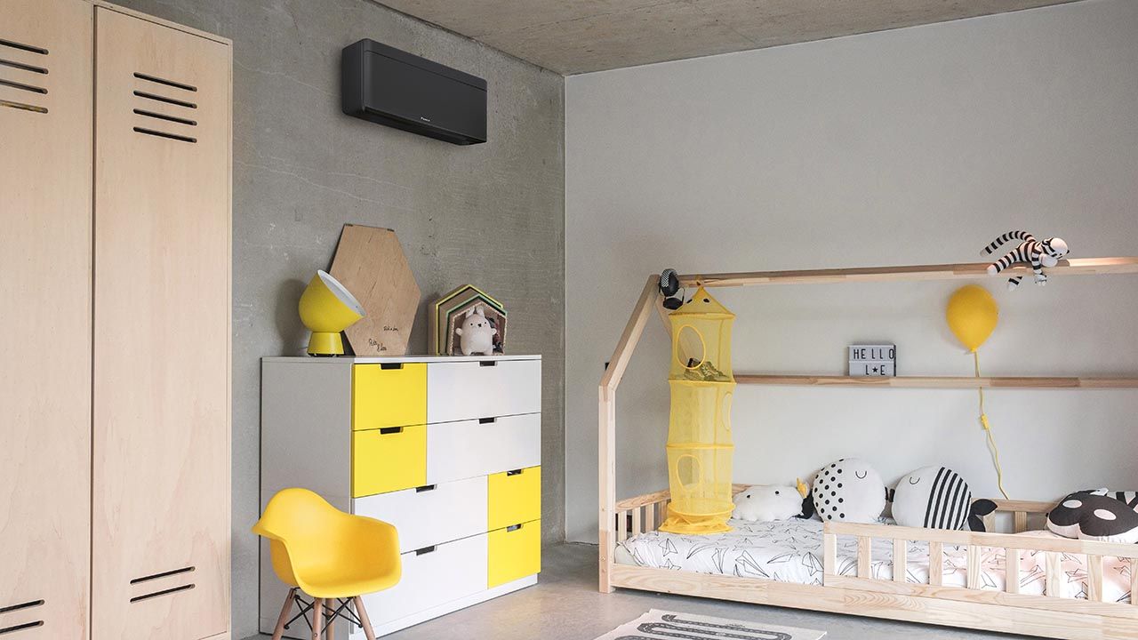 Chambre d'enfant avec un lit en forme de maison, des touches de jaune et un climatiseur mural.