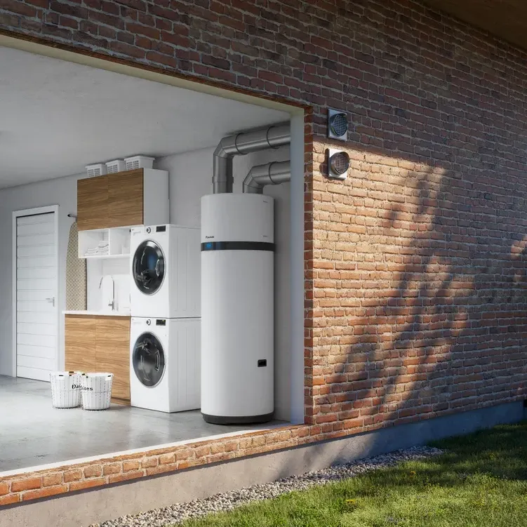Buanderie avec laveuse/sécheuse superposées, chauffe-eau, mur en briques et aérations extérieures.