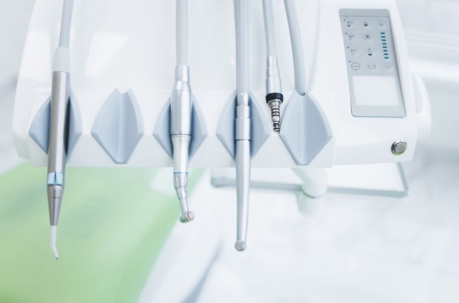 Instrumentos dentales sobre un soporte de esterilización blanco con panel de control e iluminación ambiental verde.