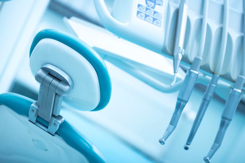 Equipo de clínica dental y reposabrazos de sillón en tonos azules en una sala de tratamiento limpia.