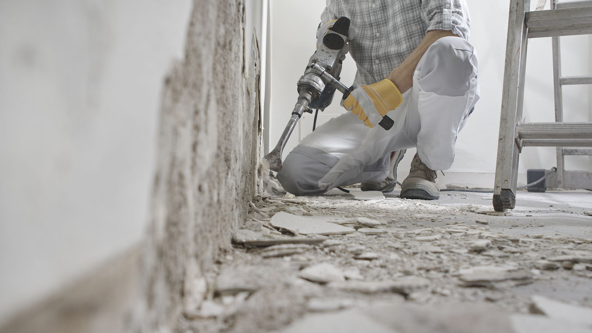Un ouvrier en train de détruire un mur intérieur