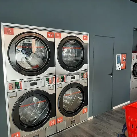 Una fila de lavadoras están apiladas una encima de otra en una lavandería automática.