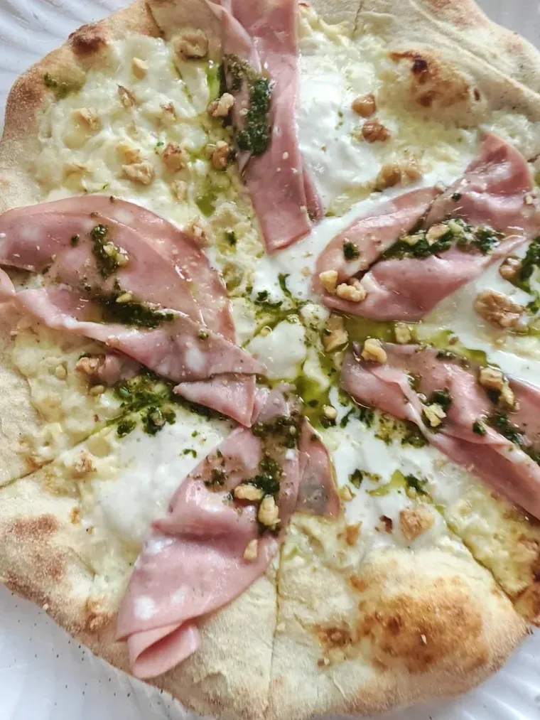 Pizza con mortadela, pesto, nueces y salsa blanca.