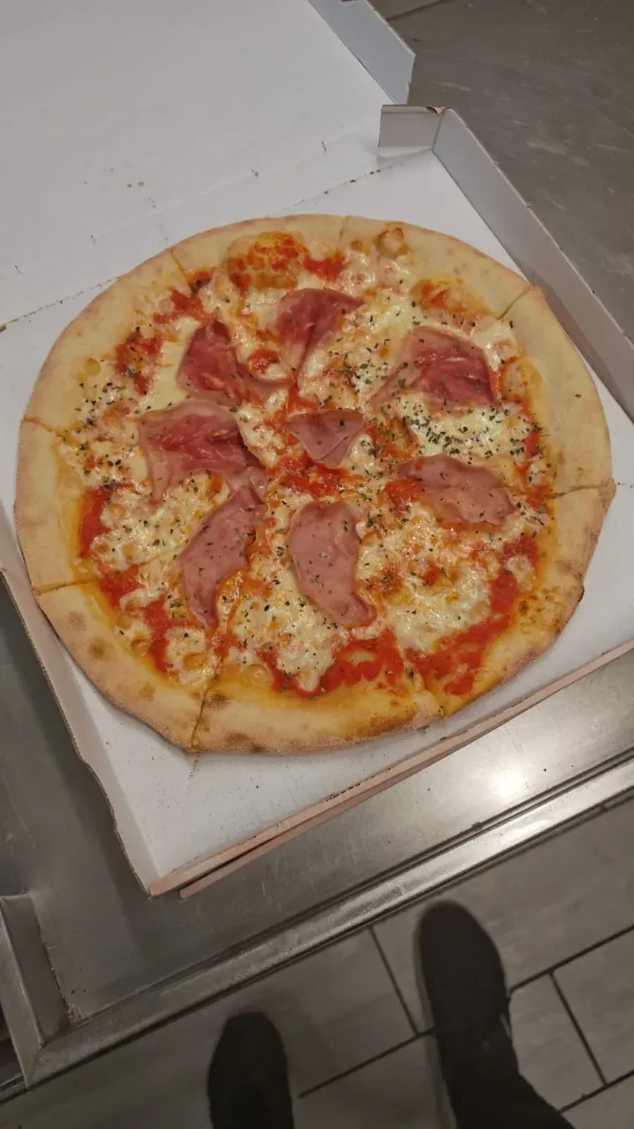 Pizza en caja de cartón, con jamón y queso.