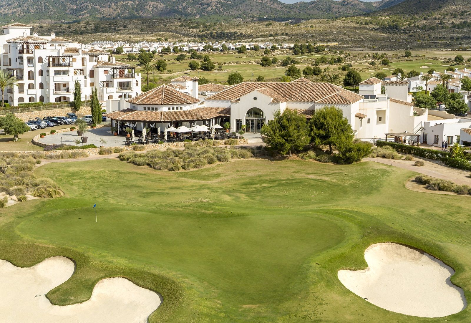 An aerial view of a golf course with a house in the background