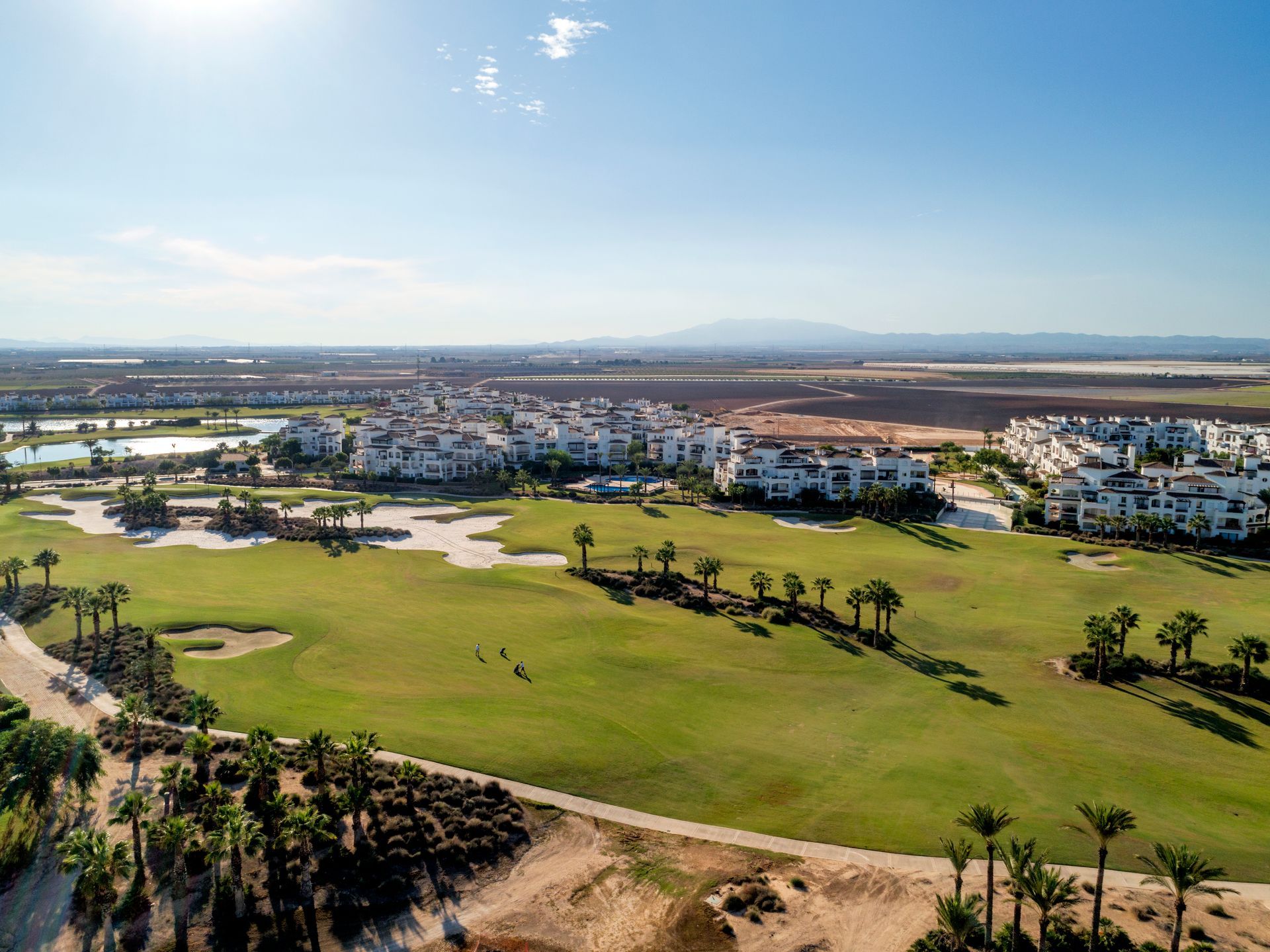 An aerial view of a golf course with houses in the background