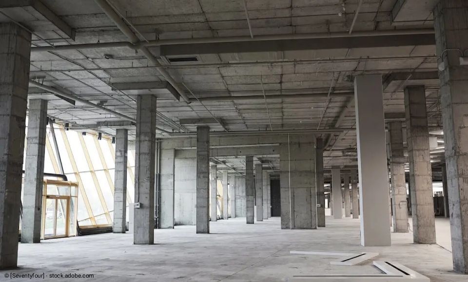 Zimmer im Umbau, Werkzeug und Holz auf dem Boden. Weiße Wände, Fenster und Deckenleuchten.